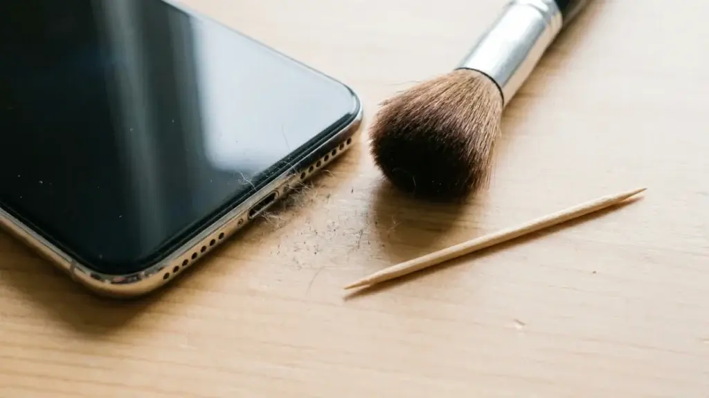 Tools used to clean a phone speaker grille including a soft brush and toothpick